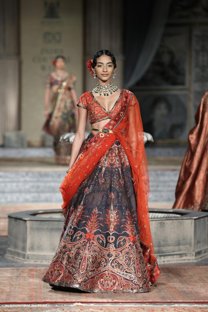 A model wearing intricate Indian wedding attire walks the runway showcasing elegance and traditional fashion.